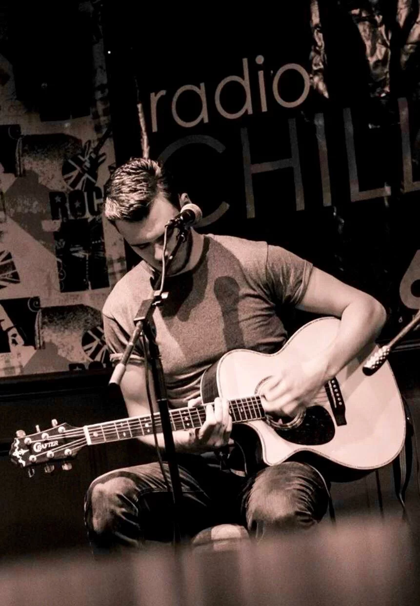 Jack Donald Guitar teacher Nottingham sat down playing an acoustic guitar